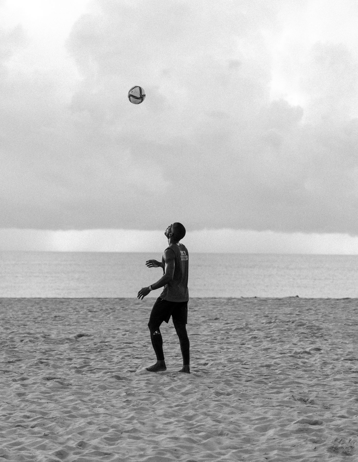 Silhouette of a player heading the ball at the shoreline